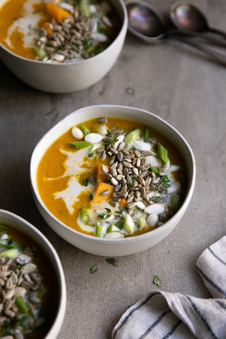 bowls full of Healthy Curry Lentil Soup showing squash cubes, seeds, green onions