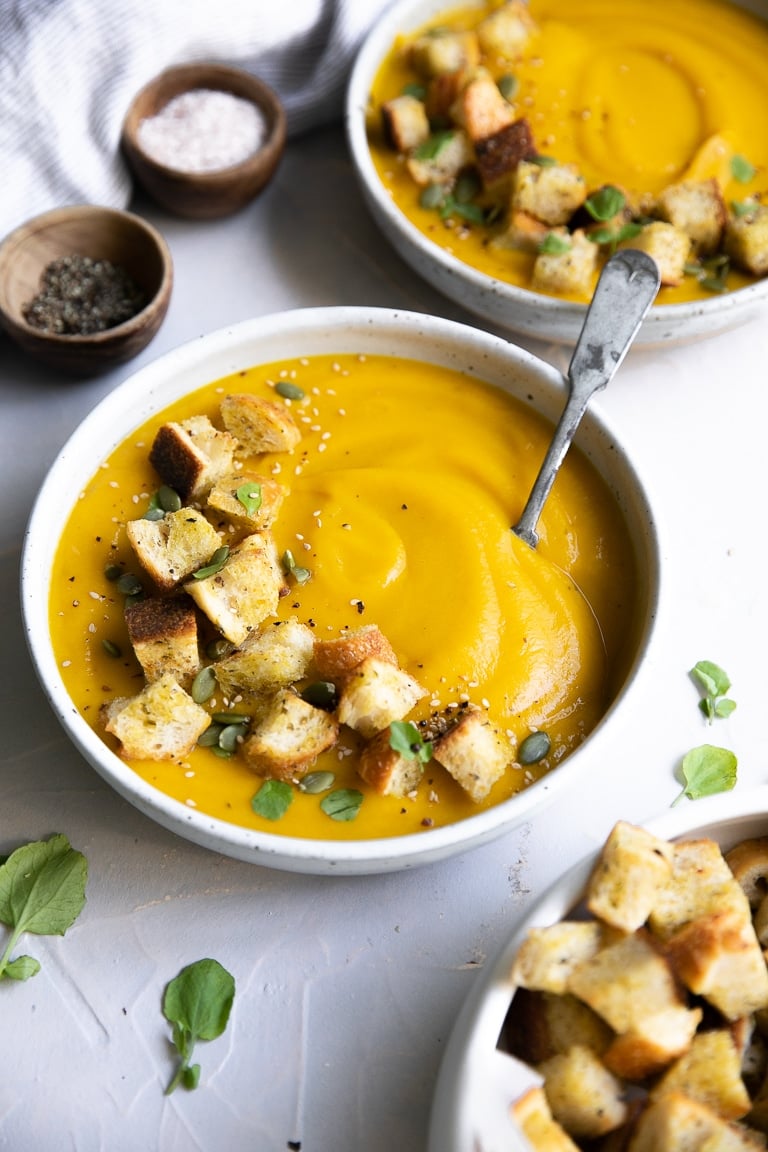 Two bowls filled with the best butternut squash soup recipe and topped with homemade croutons.