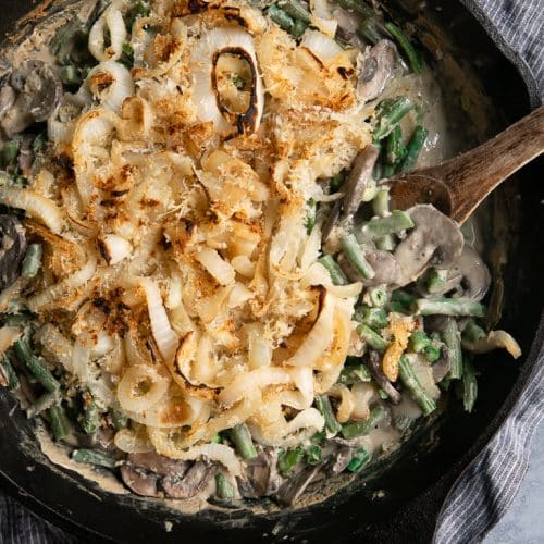 Cast Iron Skillet filled with homemade Healthy Green Bean Casserole Recipe made with homemade cream of mushroom soup and fried onions.