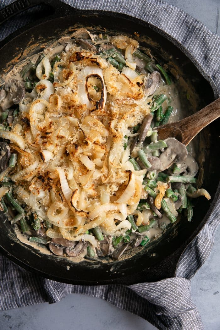 Cast Iron Skillet filled with homemade Healthy Green Bean Casserole Recipe made with homemade cream of mushroom soup and fried onions.