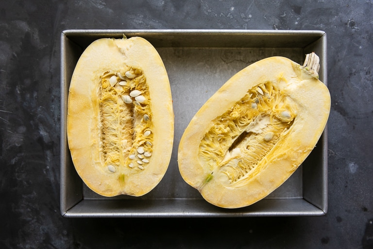 halved spaghetti squash in a baking pan