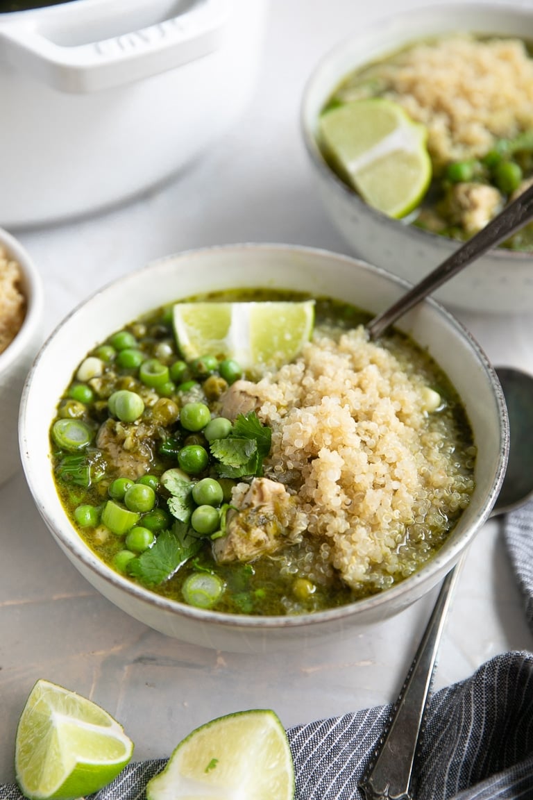 Two bowls filled with Aguadito de Pollo (Peruvian Chicken Soup) and topped with cooked quinoa.
