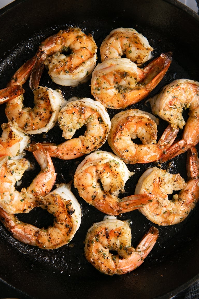 Cast iron skillet filled with juicy cooked tail-on shrimp marinated in cilantro lime marinade.