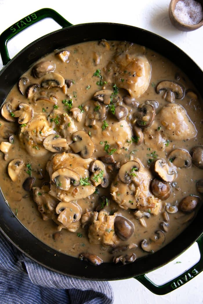Large cast iron skillet filled with prepared chicken stroganoff and garnished with fresh chopped parsley.