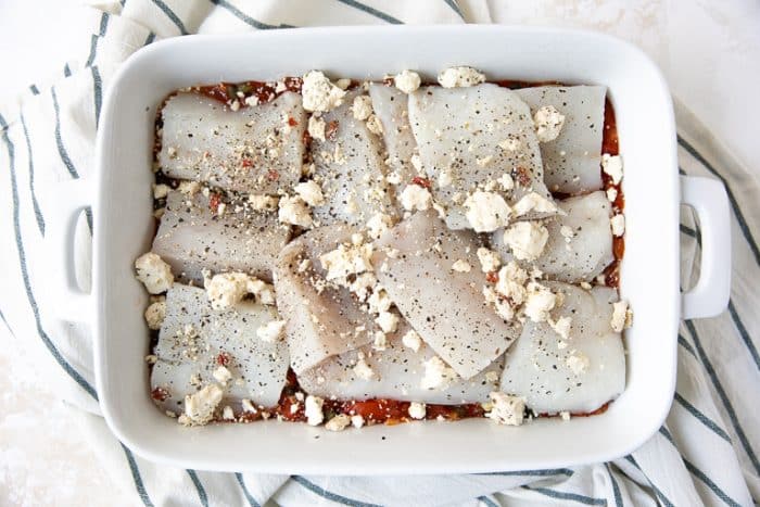 The Mediterranean baked fish in a casserole dish uncooked being put together