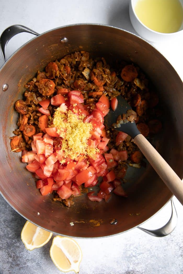 adding the garlic to the pot of Moroccan chicken stew