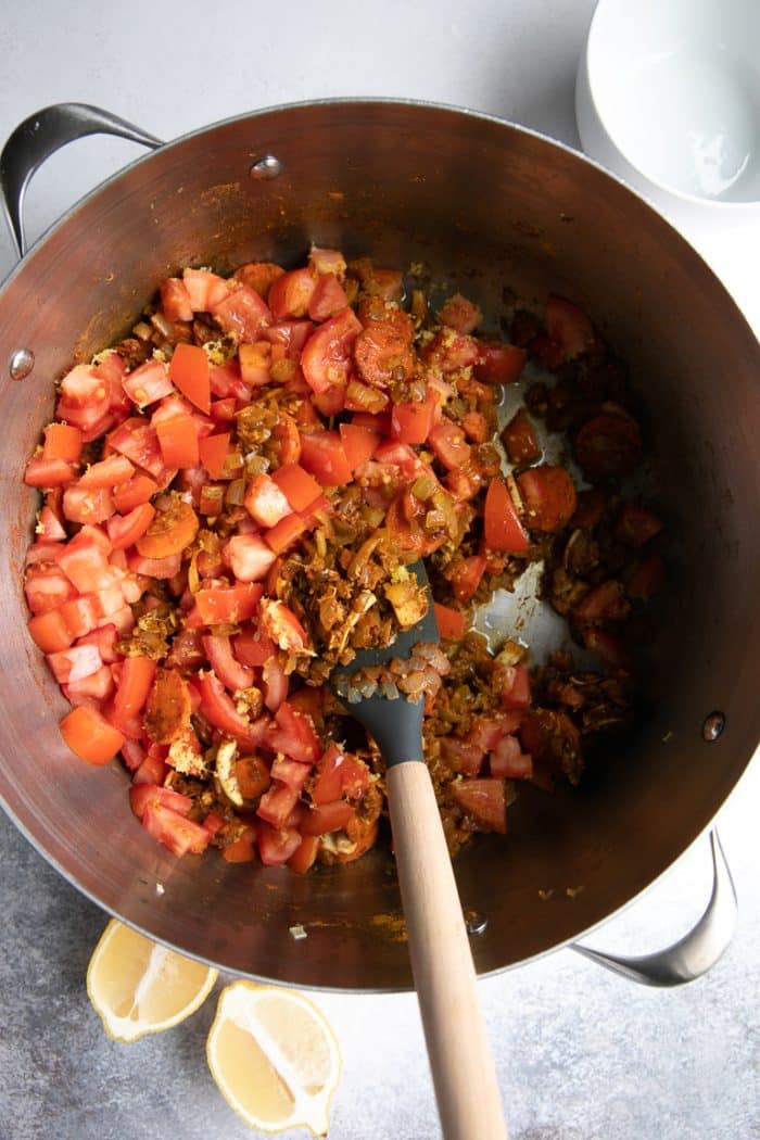 Adding paprika, salt, pepper, turmeric, coriander, fennel seeds, cumin, ground ginger, and ground cinnamon to the Moroccan chicken stew pot