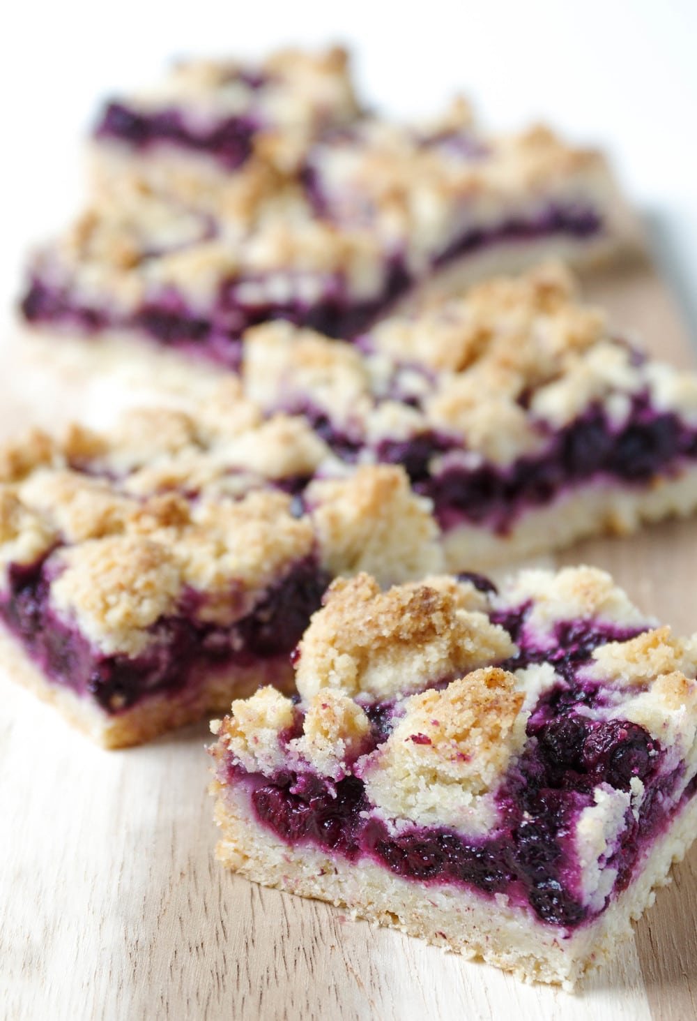 five blueberry bars squares cascading down cuttingboard.