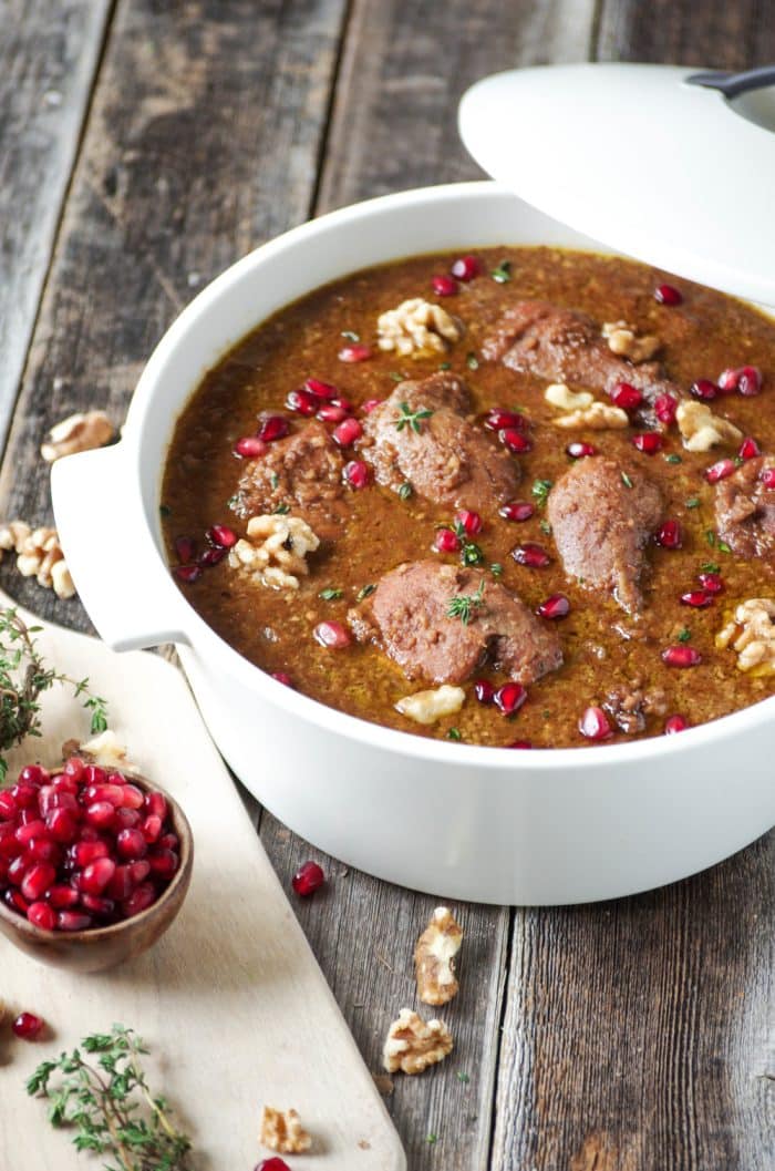 Image of a large Dutch oven filled with Fesenjān, a Iranian stew made with walnuts, pomegranate molasses, chicken, and onions.