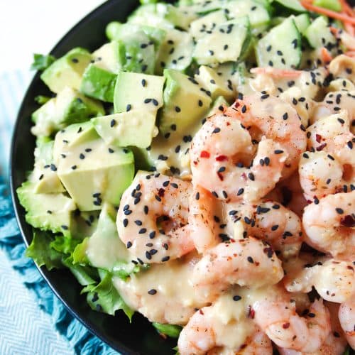 Shrimp and Avocado Salad drizzled with Homemade Miso Dressing in a black salad bowl.