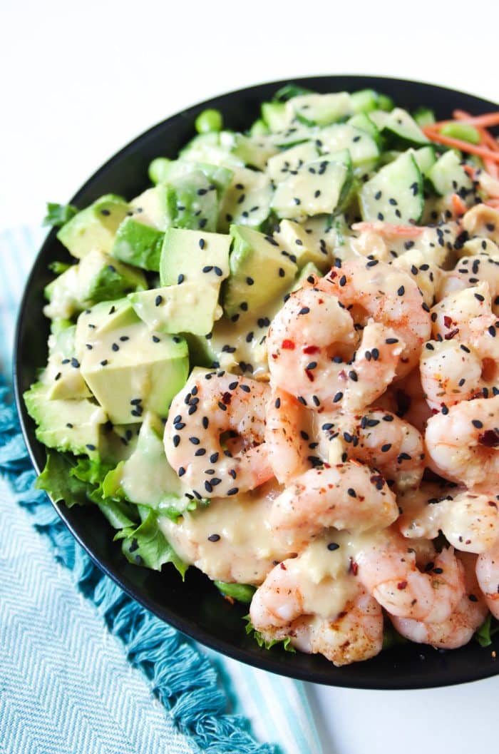 Shrimp and Avocado Salad drizzled with Homemade Miso Dressing in a black salad bowl.