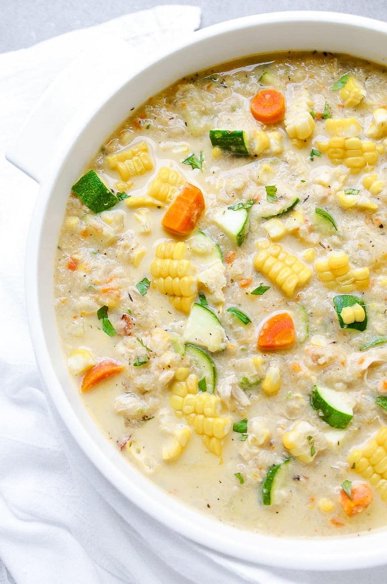 Pot of healthy summer chowder filled with corn, zucchini, carrots, chicken, and cauliflower.
