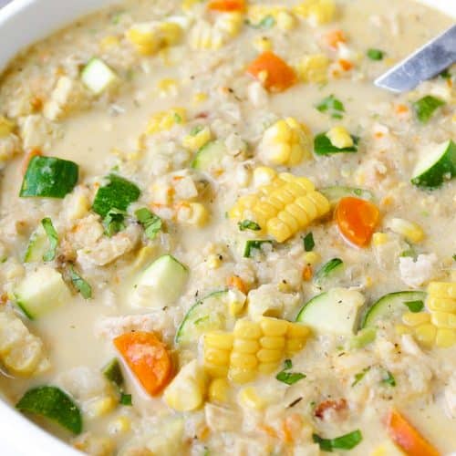 White soup pot filled with chowder made using corn, zucchini, cauliflower, and light cream as the main ingredients.