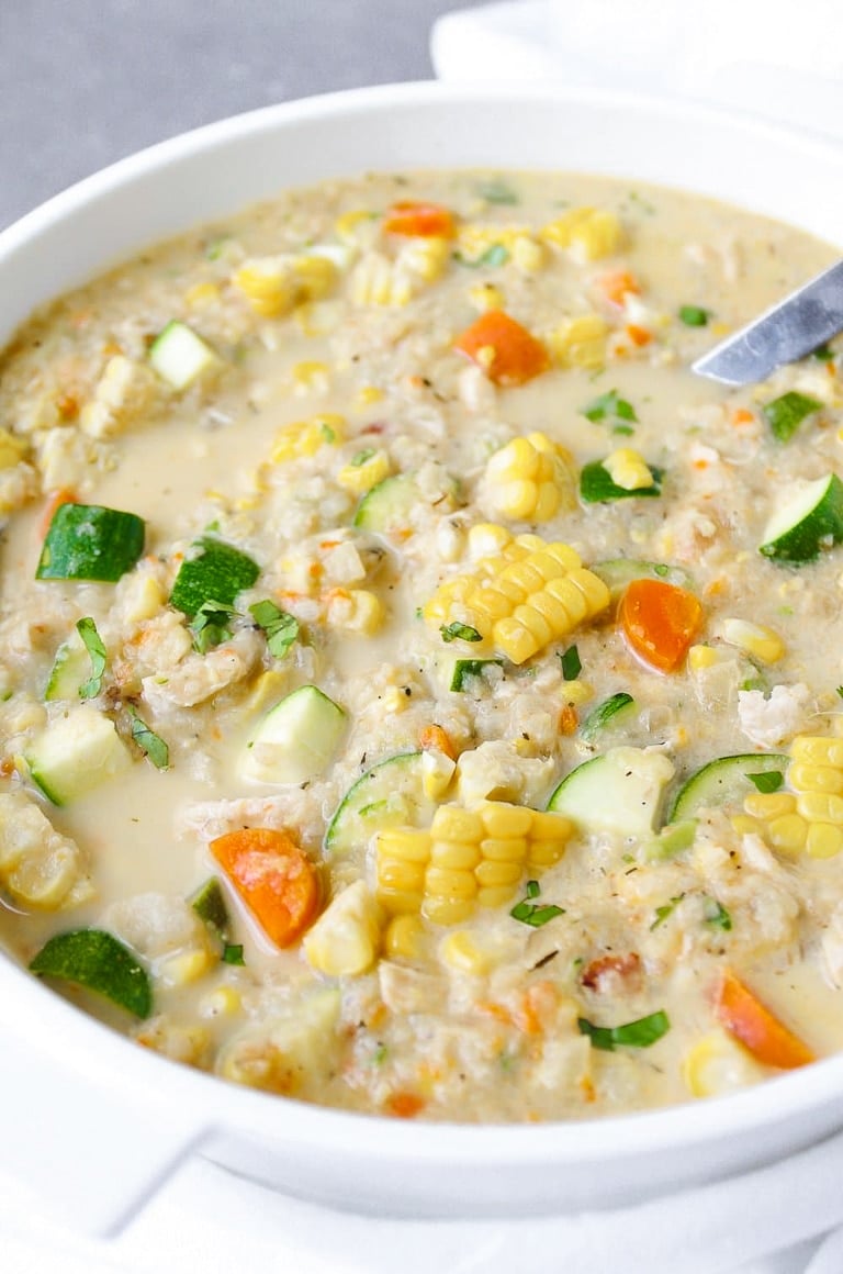 White soup pot filled with chowder made using corn, zucchini, cauliflower, and light cream as the main ingredients.