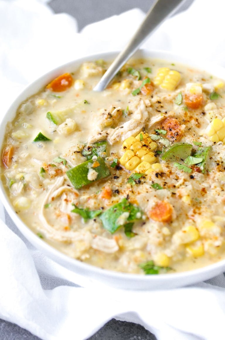 Serving of Corn Chowder garnished with chopped parsley and sprinkled with cayenne pepper.