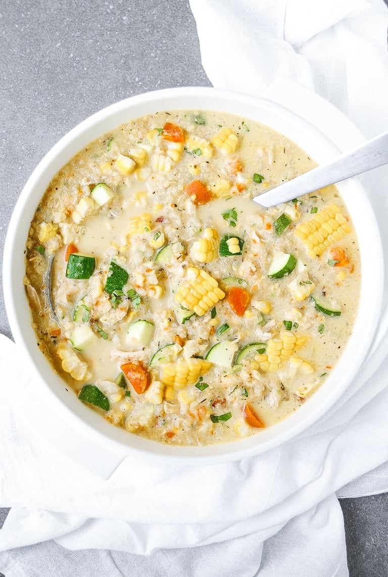 White soup pot filled with chowder made using corn, zucchini, cauliflower, and light cream as the main ingredients.