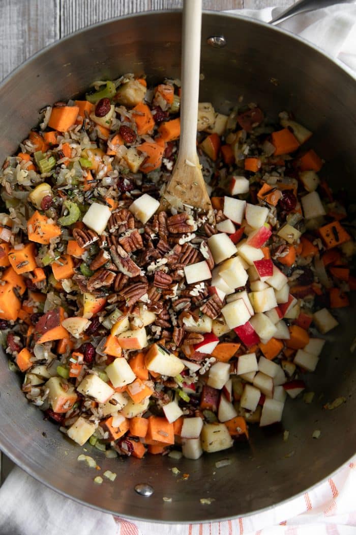 Pot filled with cooked wild rice pilaf, sweet potatoes, pecans, and apples.
