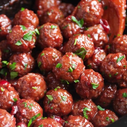 Close up image of cranberry sauce covered meatballs in a large slow cooker.
