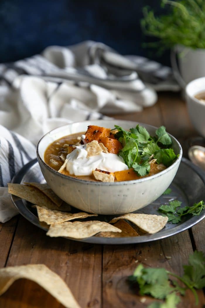 bowl of Vegetarian Butternut Squash Black Bean Soup garnished with roasted butternut squash, cilantro, tortilla chips, and sour cream