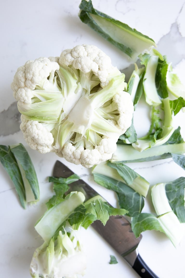 Chopping a large cauliflower into small florets.