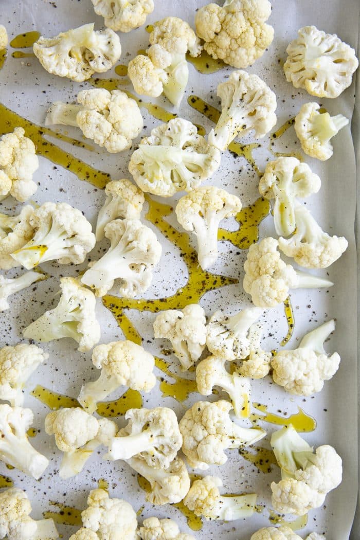 Baking sheet with cauliflower florets drizzled with olive oil and sprinkled with salt and pepper