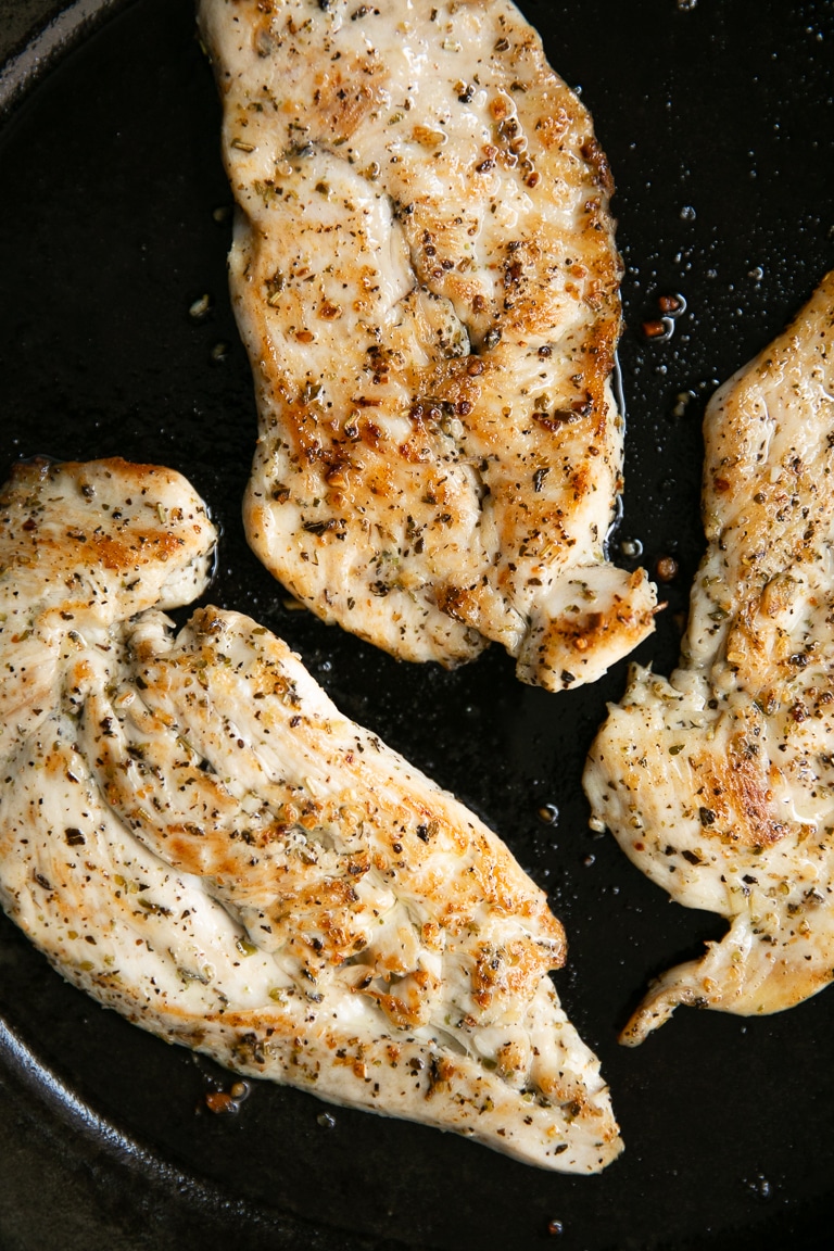 Three thinly sliced cooked chicken breasts in a cast iron skillet.