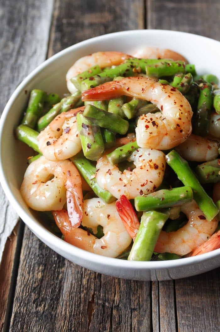 A bowl filled with meat and vegetables on a plate, with Shrimp