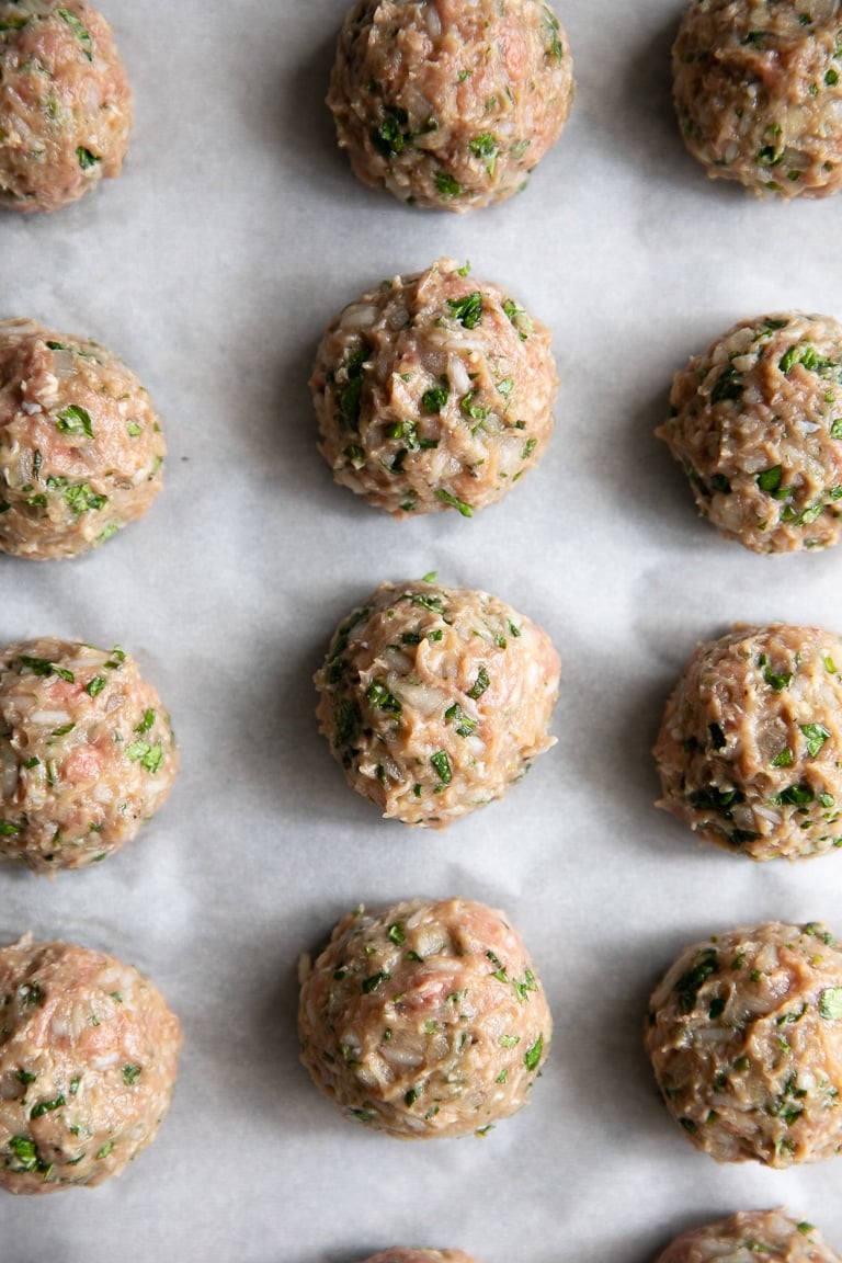 Raw albondigas meatballs rolled and set on a baking sheet ready to be cooked.