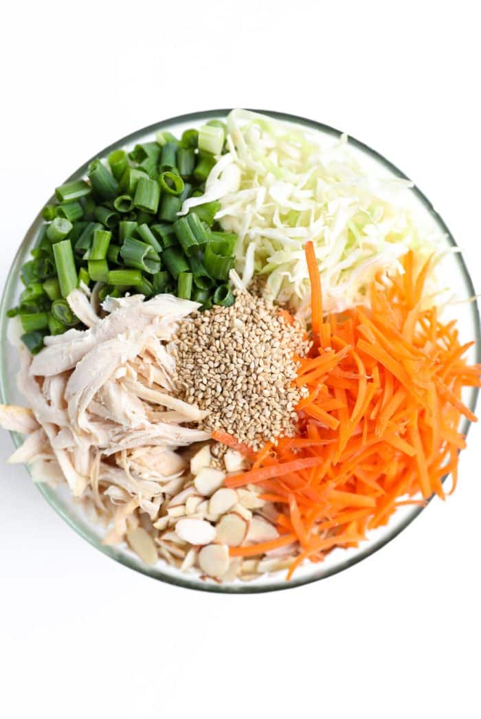 Unmixed ingredients of chicken cabbage salad in glass bowl