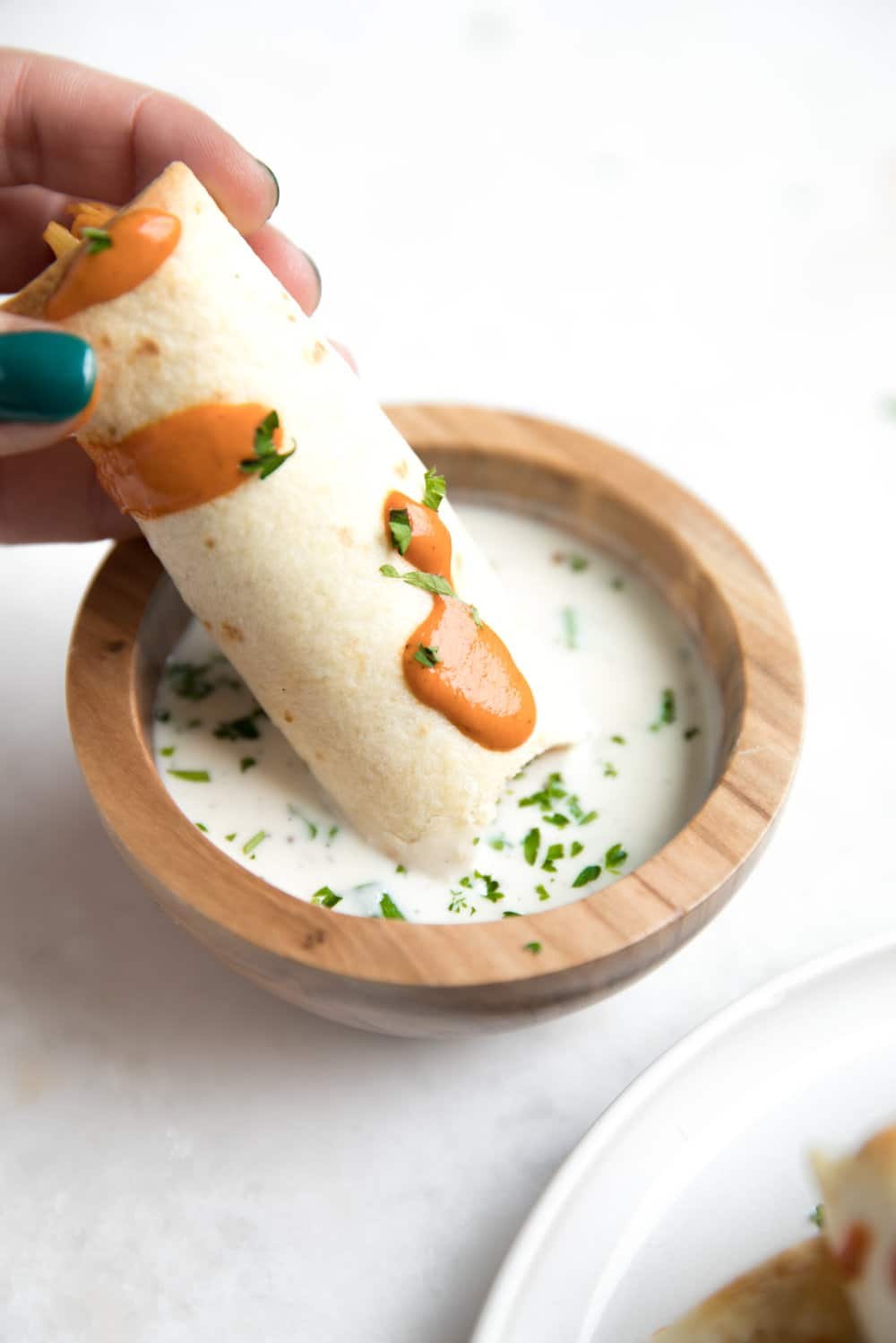 single Buffalo Chicken and Cauliflower Taquitos being dunked in ranch