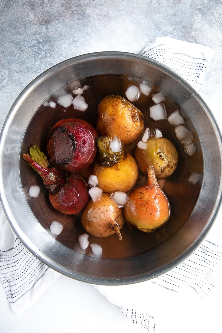 Boiled, fulled cooked beets in an ice bath.
