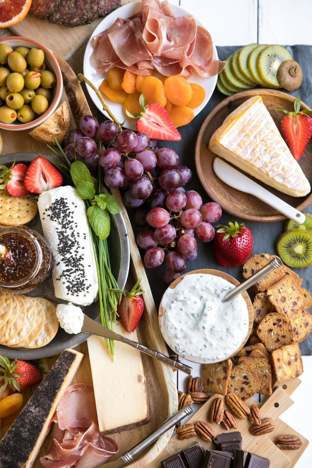 Spring Cheese Board with large assortment of meats cheese fruits and nuts with wine and chocolates