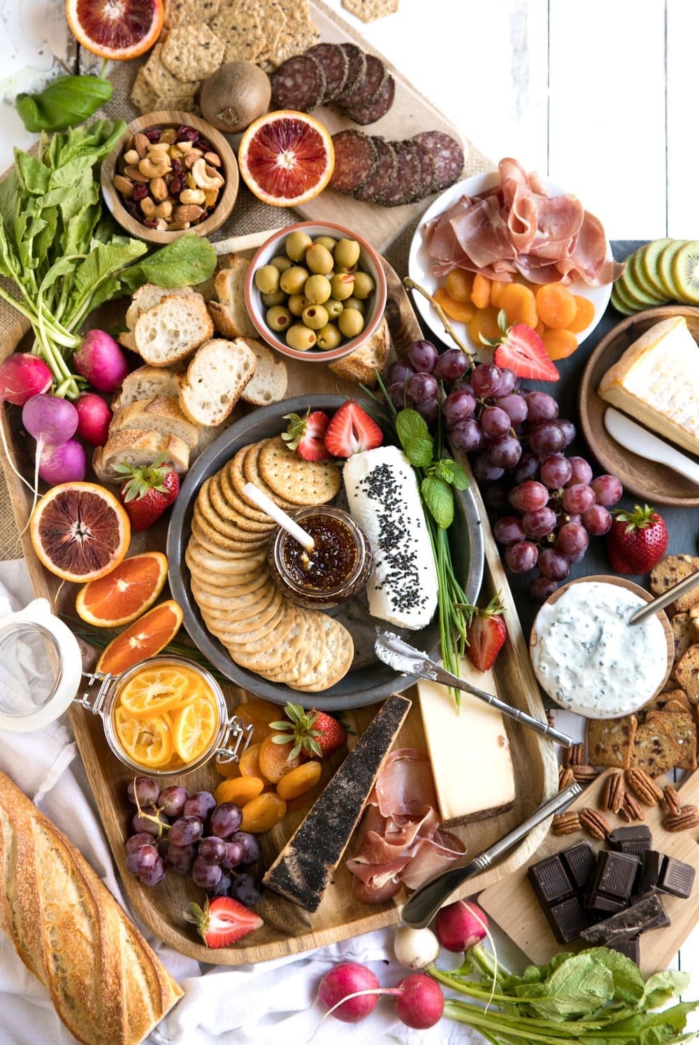 close up of Spring Meat and Cheese Board with large assortment of meats cheese fruits and nuts with wine