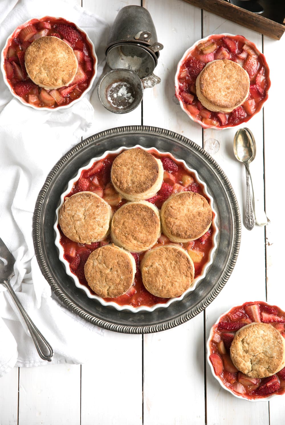 Strawberry Rhubarb Cobbler in large dish with single servings surround it