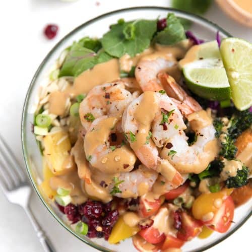 A bowl of food on a plate with shrimp salad buddha bowl