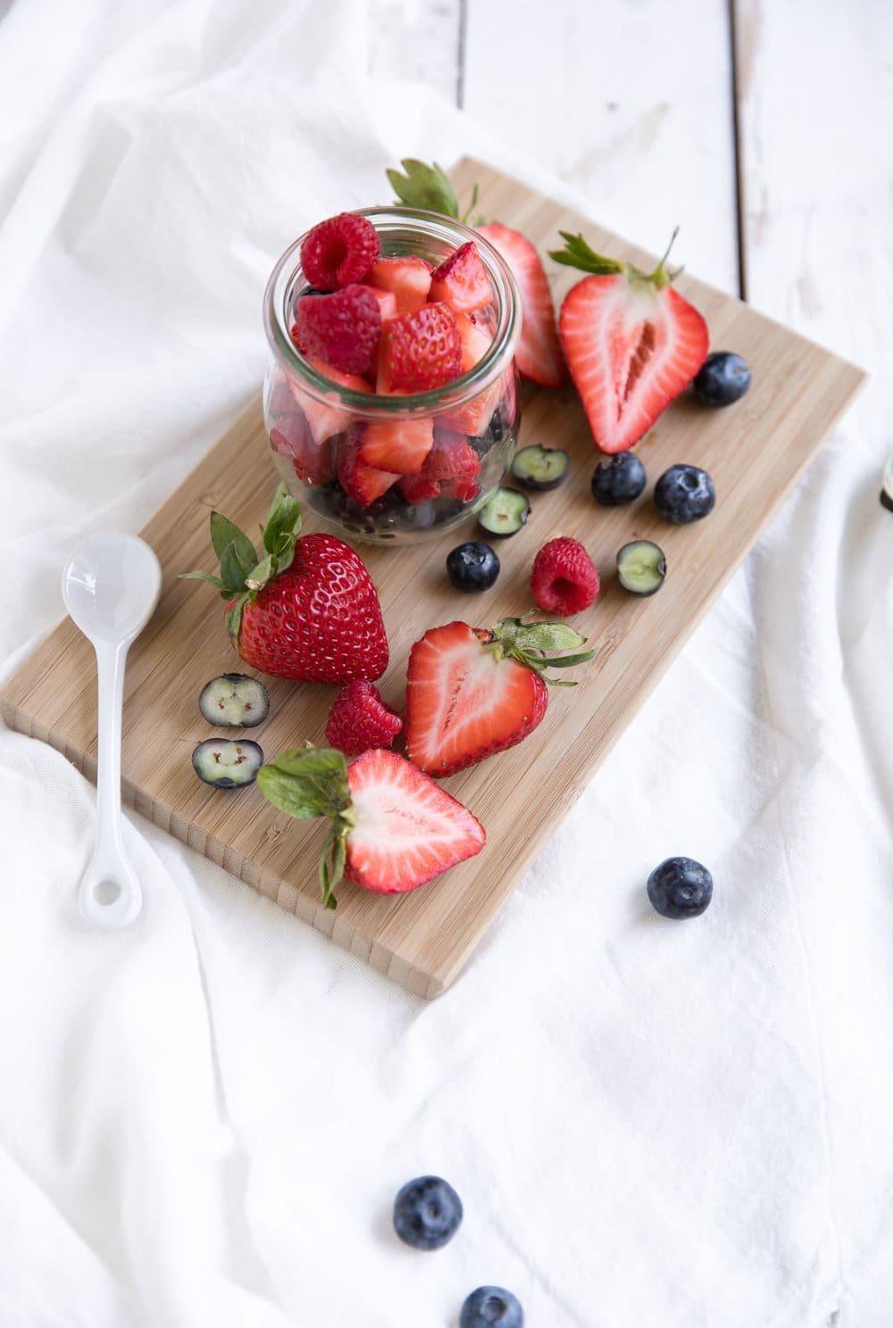 glass filled with sliced strawberries, blueberries, and raspberries