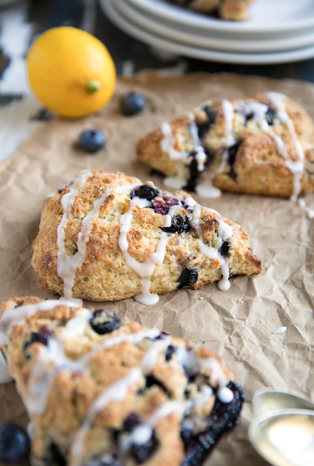 Close up of three blueberry scones in a row followed by plates and a lemon