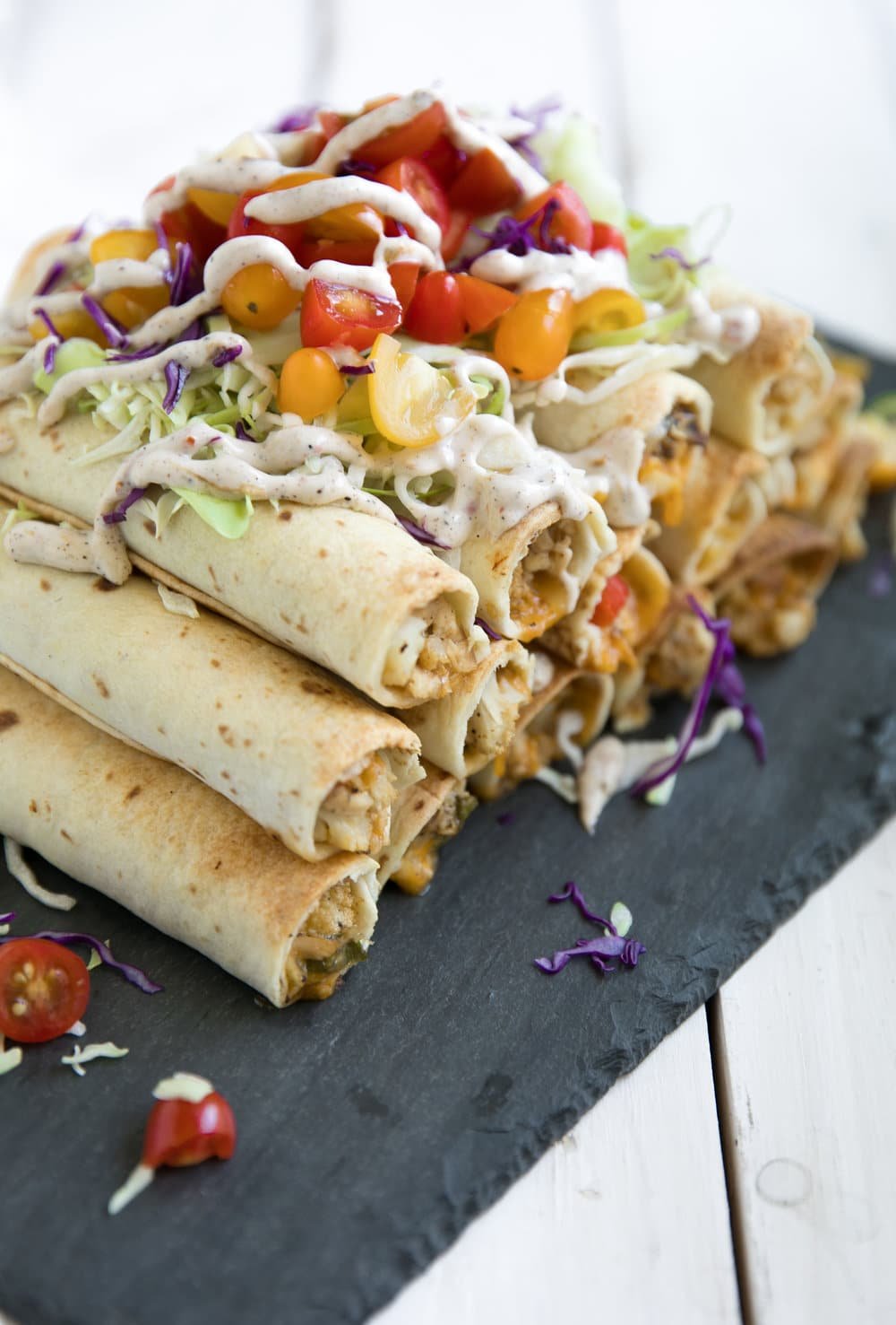 pile of Jerk Chicken and Cauliflower Taquitos covered in vegetables and sauce