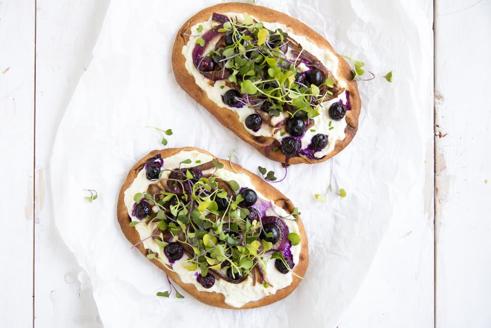 overhead shot of two Blueberry and Honey Caramelized Onion Naan Pizzas