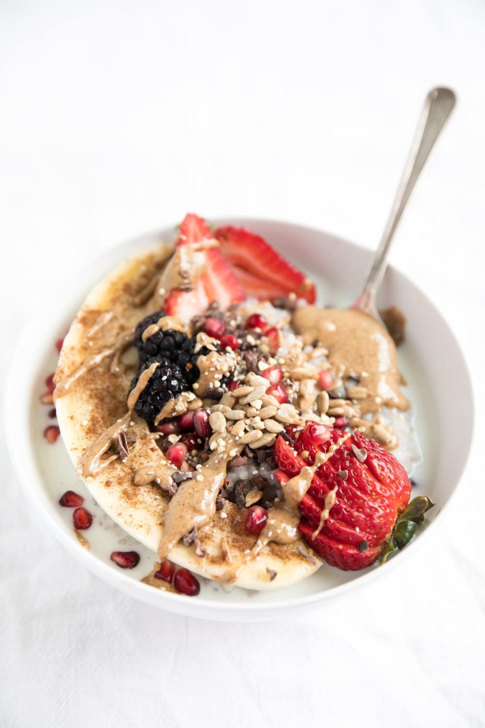 diagonal photo of Buckwheat Oatmeal Breakfast Bowl covered in seeds strawberries and peanut butter