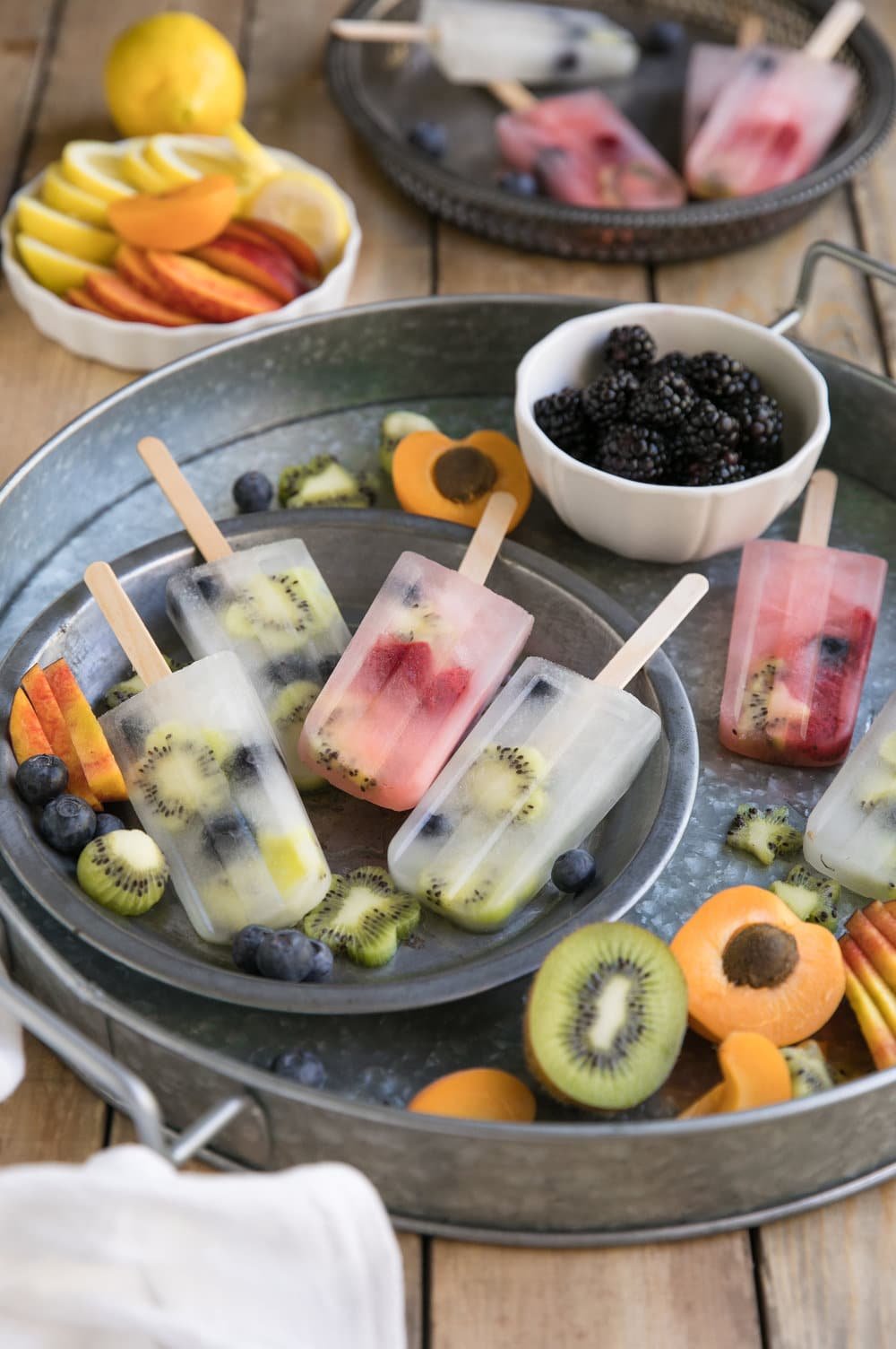 Homemade lemonade and fruit popsicles on a metal serving tray.