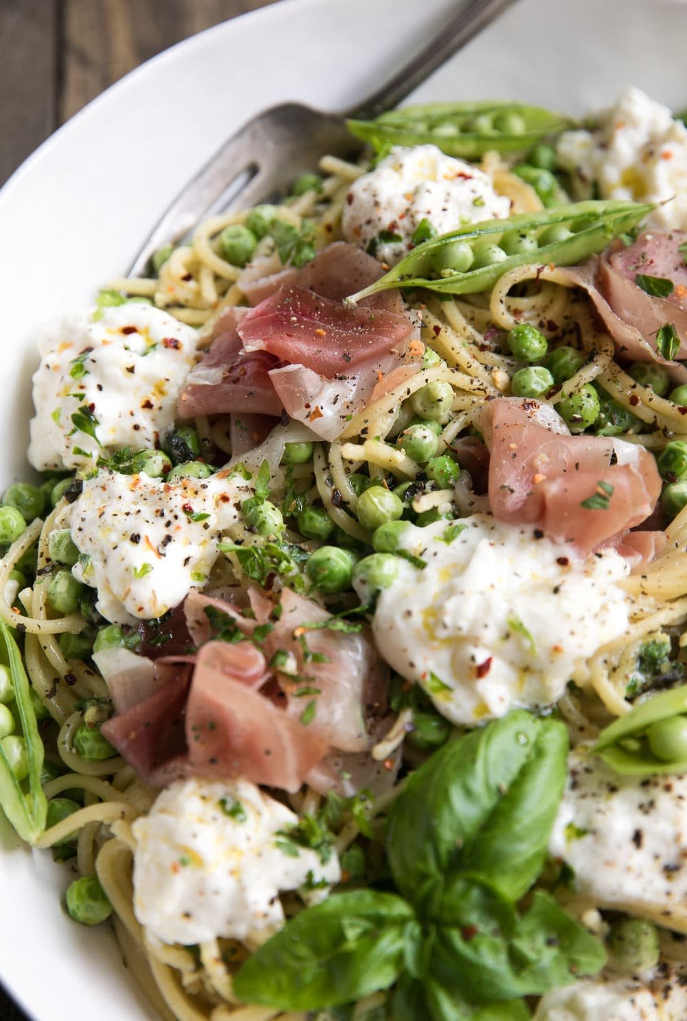 Noodles, salty prosciutto, and cheese mixed in a bowl