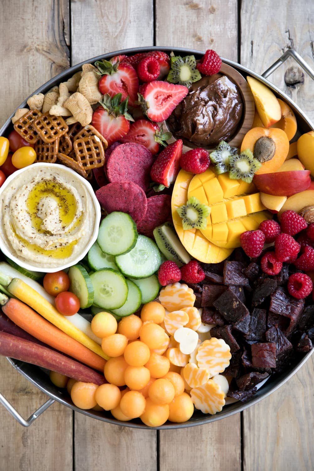 Bright, colorful, and jam-packed with delicious snacks both kids and adults will love, this super easy Kid-Friendly Charcuterie Board will be the highlight of any party! Filled with fresh fruit, cheese, meat snacks, nutella, hummus, and fresh chopped veggies.