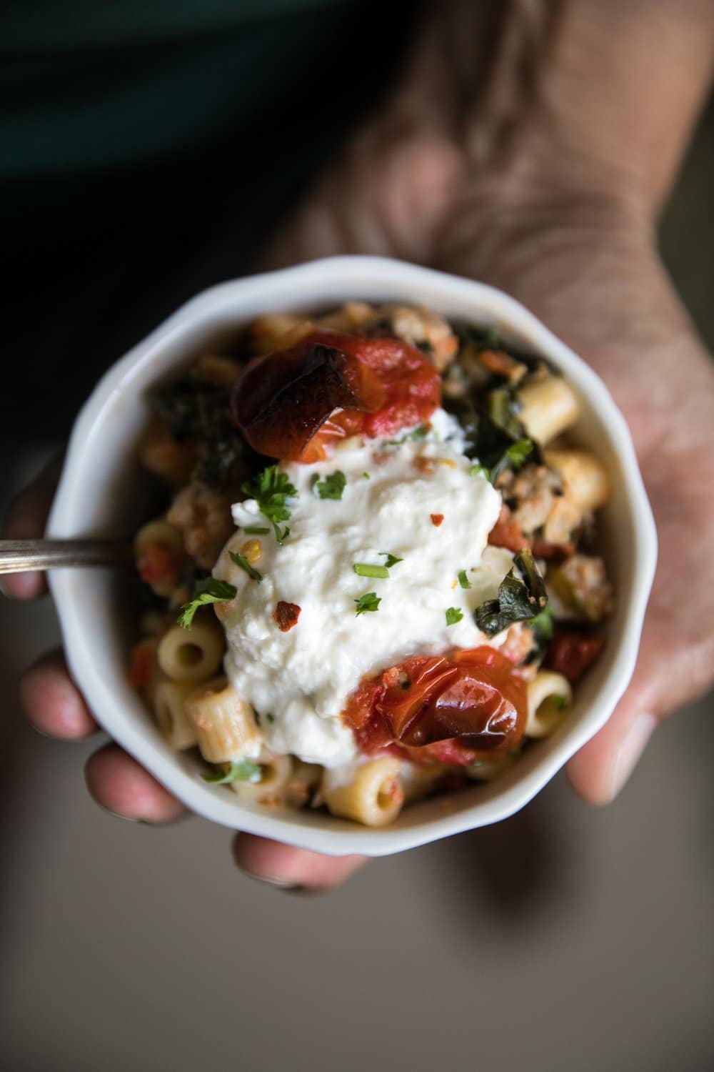 small hand held bowl of Creamy Sausage Pasta with Kale and Burrata