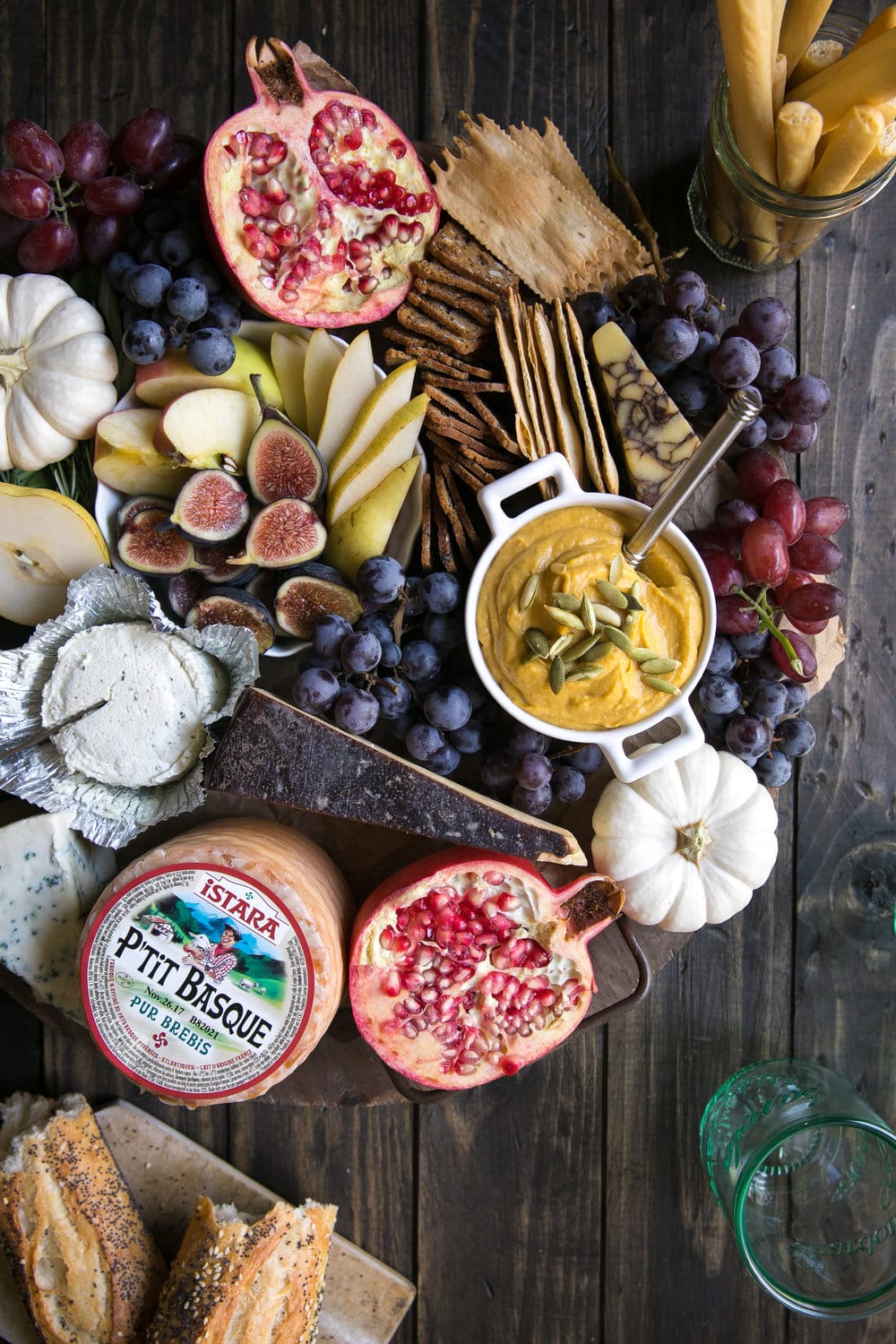 A bunch of fruits and cheeses sitting on top of a wooden cheese board