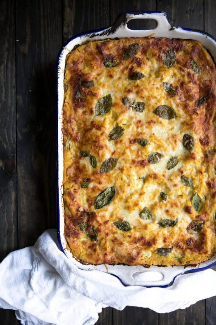 A lasagna made with butternut squash, zucchini, spinach and cheeses in a large casserole dish