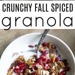 Bowl of crunchy fall spiced granola topped with pomegranate seeds and served with milk.