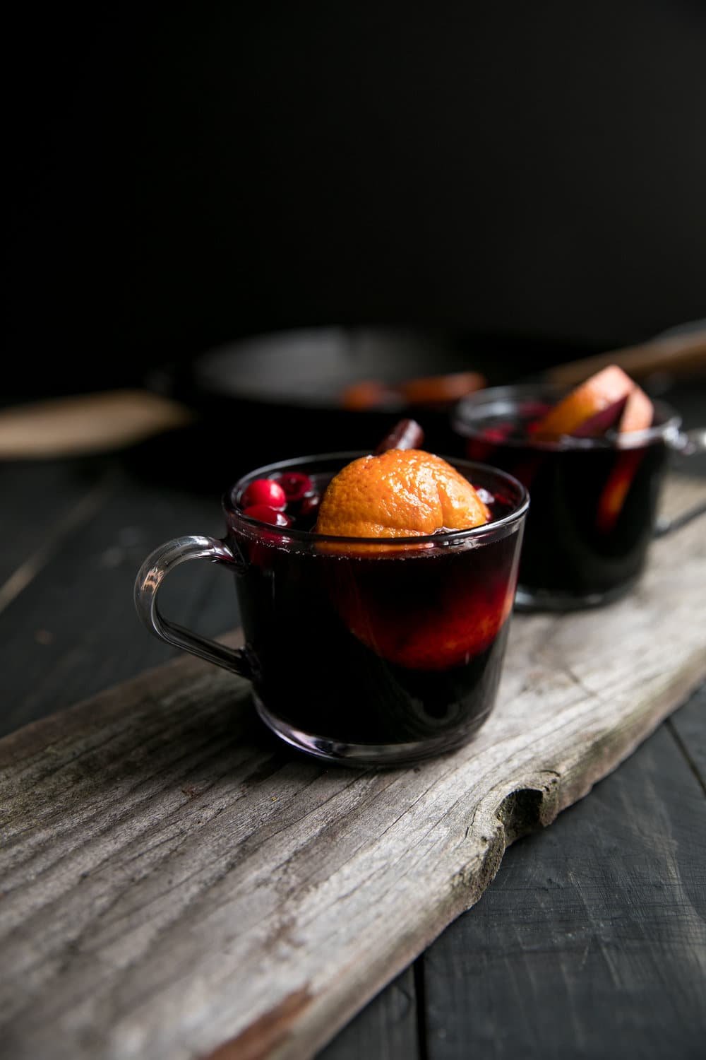 Two glass mugs filled with mulled wine sitting on top of a wooden table