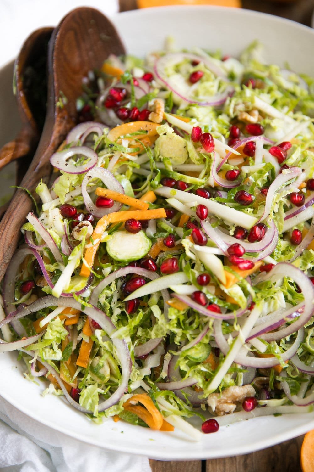 Shredded Brussels Sprout Persimmon Salad. Filled with some of falls finest like pomegranates, walnuts, pomegranates, apples, Brussels sprouts and drizzled with light dijon vinaigrette.