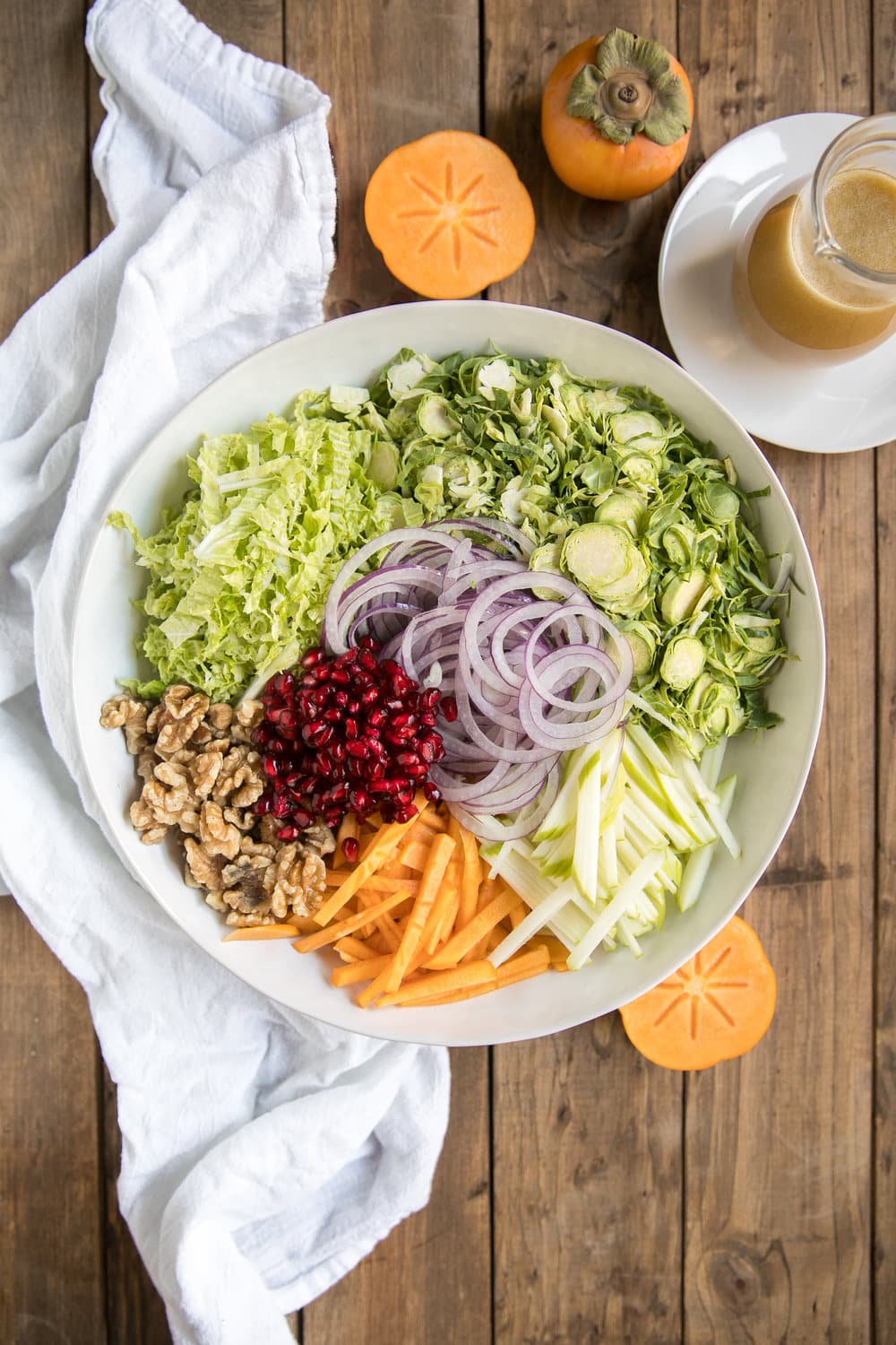 Shredded Brussels Sprout Persimmon Salad. Filled with some of falls finest like pomegranates, walnuts, pomegranates, apples, Brussels sprouts and drizzled with light dijon vinaigrette.